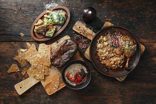Traditional Danish Slow Cooker Duck Leg Confit with spelled wheat cereal and cereal chips. Flat lay top-down composition on wooden background. Horizontal image with copy space.