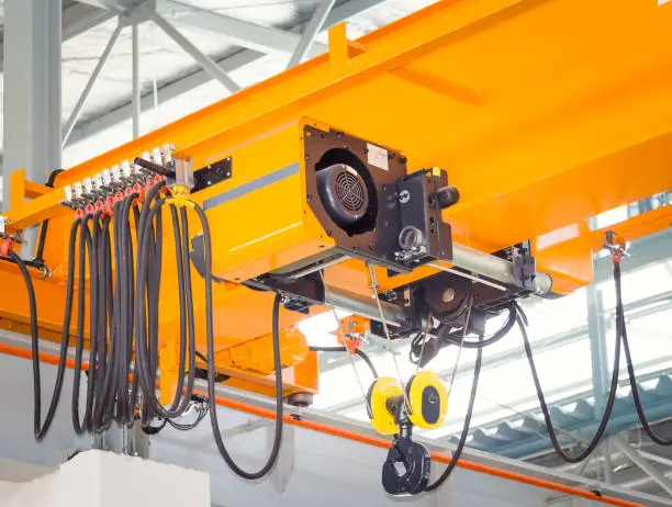 Photo of Overhead crane and hook on steel beam with factory wall background.