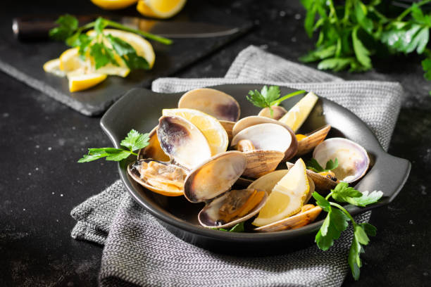 istock Cooked clams in a black ceramic plate on the black kitchen table. Seafood dish 1253809434