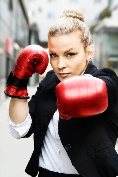 femme d’affaires dans des gants rouges de boxe. elle est combattante pour le succès. - women business strength boxing photos et images de collection