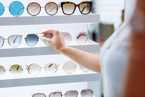 Hands putting fashionable black sunglasses back on enlighted shelf