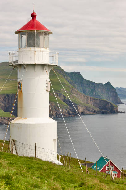Mykines lighthouse and cliffs on Faroe islands. Hiking landmark Mykines lighthouse and cliffs on Faroe islands. Hiking landmark. Denmark mykines faroe islands photos stock pictures, royalty-free photos & images