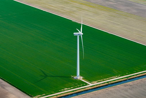 Aerial view of a wind turbine in Flevoland standing in between   fields growing crops in spring The Netherlands.