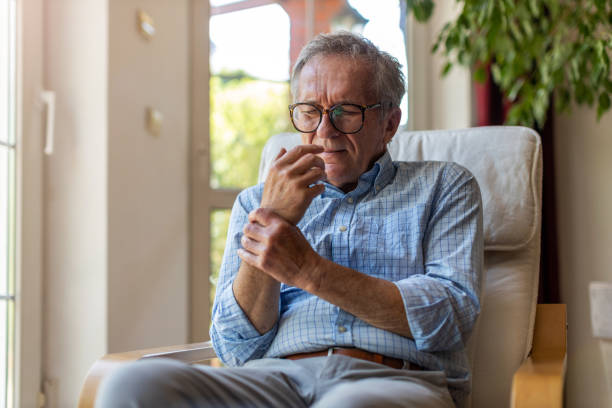 homme aîné avec les mains de frottement d’arthrite - poignet photos et images de collection