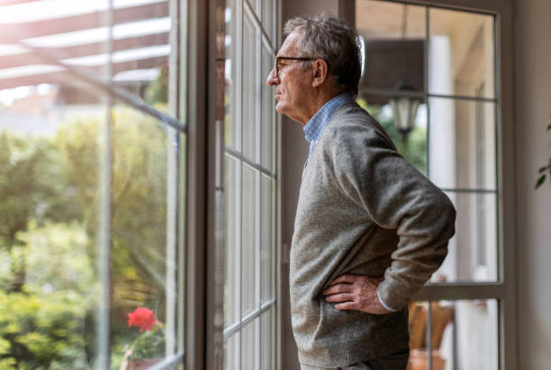 istock Senior man looking out of window at home 1253815521