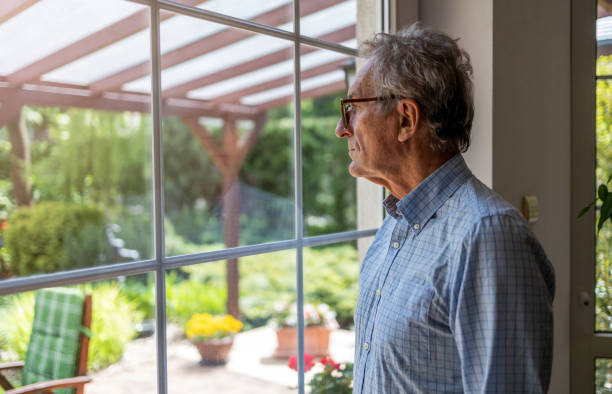 istock Senior man looking out of window at home 1253815565