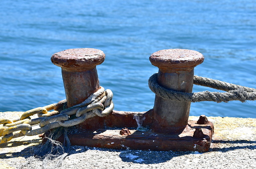 Old rusty mooring bollard close-up in a dock.