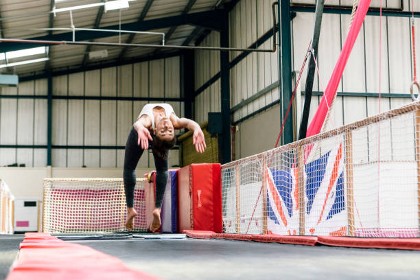 Female gymnast practicing back handspring Low angle view of 30 year old Caucasian female athlete doing back handspring on exercise mat in British gymnastics club. handspring stock pictures, royalty-free photos & images