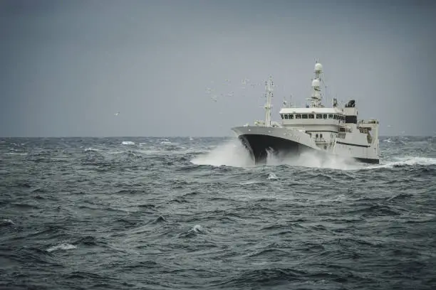 Photo of Fish boat vessel fishing in a rough sea: industrial trawler