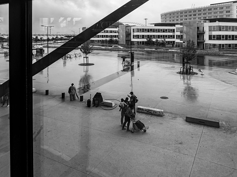 Saint Exupery Airport in Lyon, France. This is a view through windows to the outside of the airport and people leaving the airport or waiting for friends or transport.