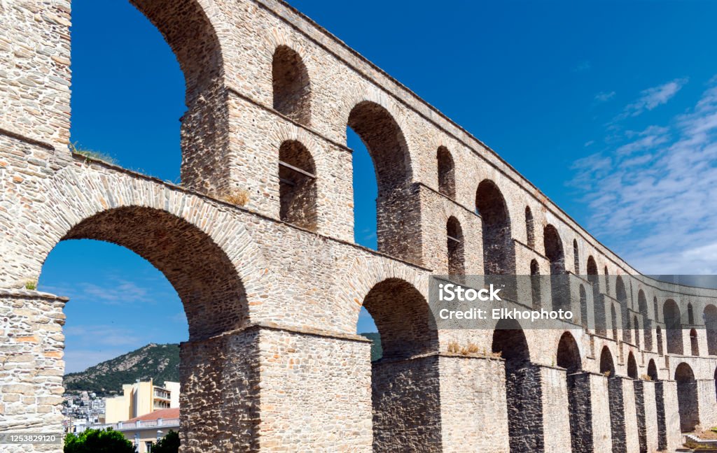 Ancient aqueduct Kamares - historical heritage and architectural landmark in Greek city Kavala, eastern Macedonia, Greece. Medieval aqueduct, blue sky in background. Copy space Kavalla Stock Photo