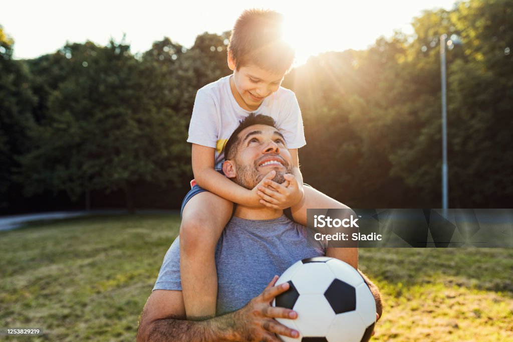 We are always happy when  spending time together Happy hispanic father play soccer with his cute son.They enjoy in nature and nice summer sunset. Soccer Stock Photo