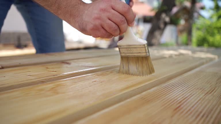 Applying protective varnish on a wooden boards.