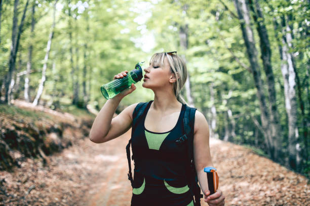 istock Female Blonde Drinking Water While Hiking In Mountain 1253830562