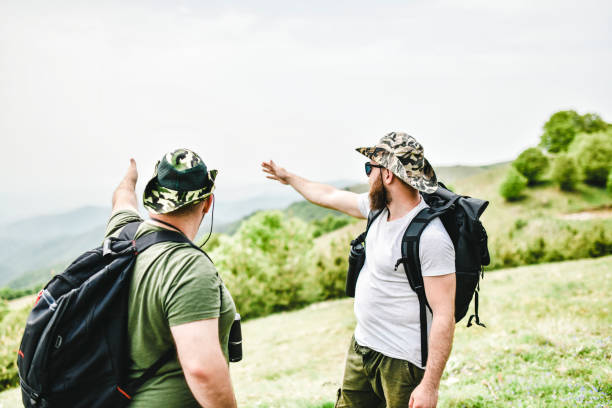 istock Males Overlooking Valley Under Mountain Where They're Hiking 1253831456