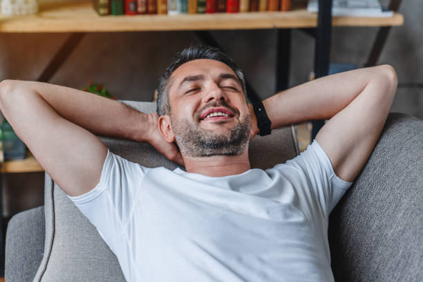 istock Middle aged relaxed man resting lying on couch with the hands on the head at home 1253833608