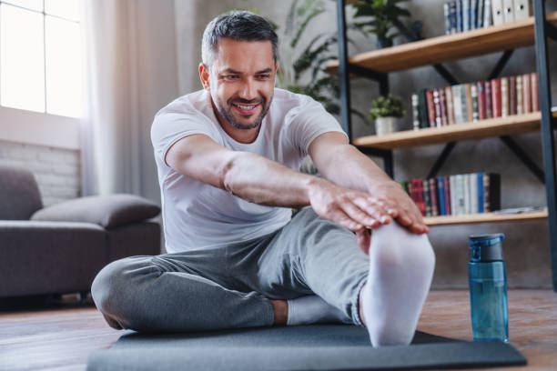 homme beau faisant l’exercice d’étirement d’ischio-jambiers à la maison. - home fitness photos et images de collection