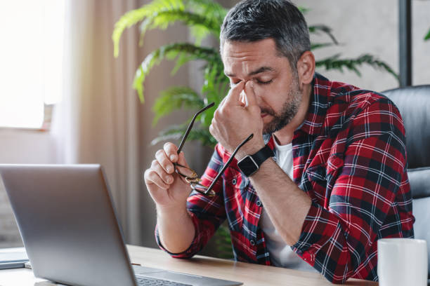 Tired caucasian man suffer from headache bad vision sight problem sitting at home table using laptop Tired caucasian man suffer from headache bad vision sight problem sitting at home table using laptop Tensed stock pictures, royalty-free photos & images