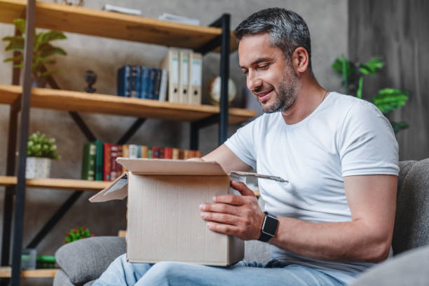 istock Happy middle aged man with cardboard boxes delivery at home 1253834448
