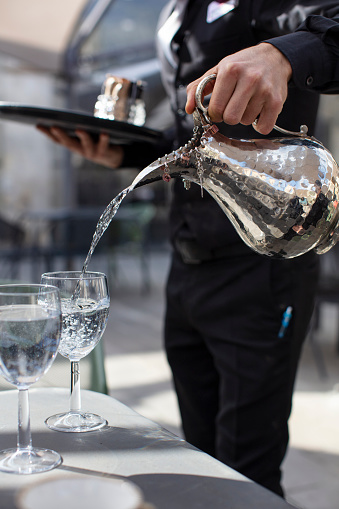 Pouring Water in Glass with Silver Carafe