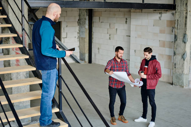 istock Bald young contractor or foreman with touchpad standing on staircase by railings 1253835020