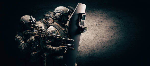 Image of three soldiers in a shooting computer game. ESports concept. They hide behind a tactical bulletproof shield. stock photo