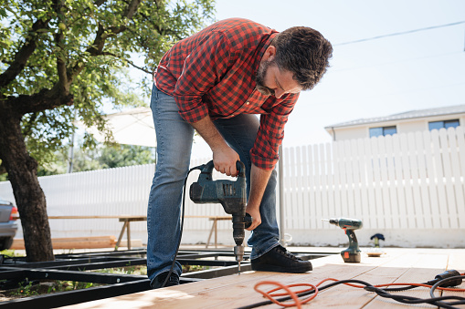 Carpintero instalando una terraza exterior de suelo de madera en obra de construcción de nueva casa photo