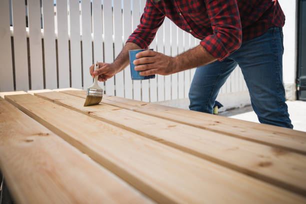 istock Carpenter paints a wooden floor planks, in new house construction site 1253841002