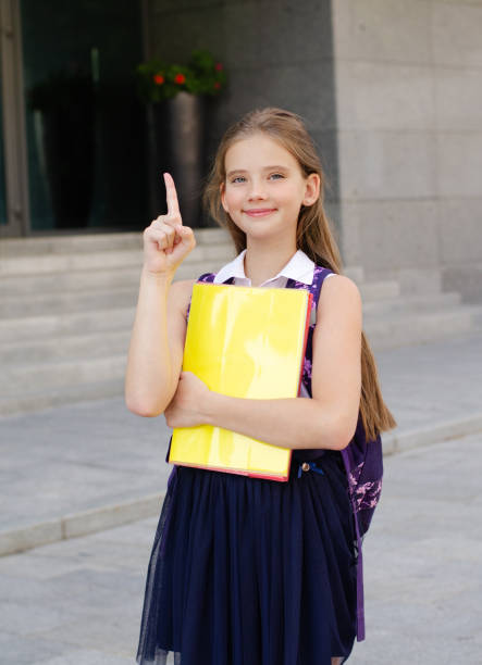 Back to school. Education concept. Cute smiling schoolgirl on the way to the schoo Back to school. Education concept. Cute smiling schoolgirl on the way to the school. Happy little girl child holding the books with backpack and pointing up by forefinger back to schoo stock pictures, royalty-free photos & images