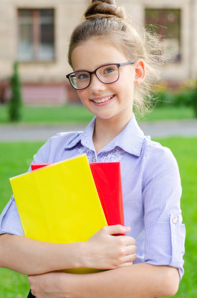 Back to school. Education concept. Cute smiling schoolgirl on the way to the schoo Back to school. Education concept. Cute smiling schoolgirl on the way to the school. Happy little girl child in glasses holding the books back to schoo stock pictures, royalty-free photos & images
