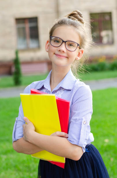 Back to school. Education concept. Cute smiling schoolgirl on the way to the schoo Back to school. Education concept. Cute smiling schoolgirl on the way to the school. Happy little girl child in glasses holding the books back to schoo stock pictures, royalty-free photos & images