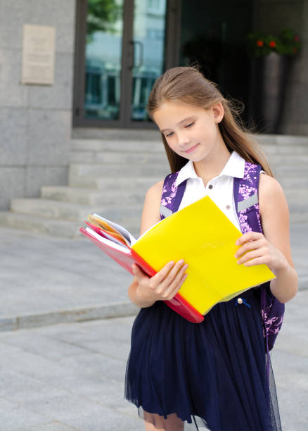 Back to school. Education concept. Cute smiling schoolgirl on the way to the schoo Back to school. Education concept. Cute smiling schoolgirl on the way to the school. Happy little girl child reading the books with backpack back to schoo stock pictures, royalty-free photos & images