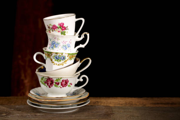 Various vintage porcelain teacups with floral decoration on dark background. Stack of various English vintage porcelain teacups with floral decoration on dark background. tea cup and saucer stock pictures, royalty-free photos & images