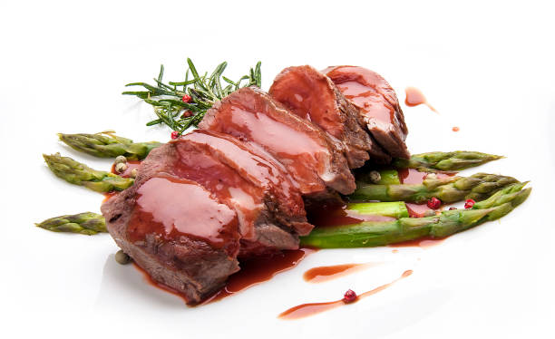 Veal fillet with asparagus and sauce, on white background Veal fillet with asparagus and sauce, on white background celebrity roast stock pictures, royalty-free photos & images