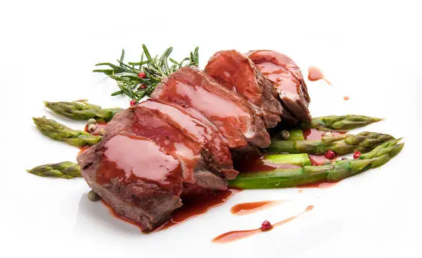 Veal fillet with asparagus and sauce, on white background
