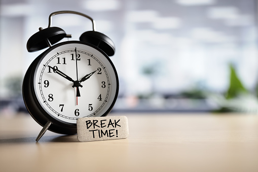 Break time concept message with alarm clock on desk in office