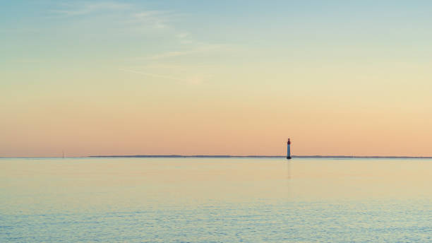 Chassiron lighthouse, isle of Re, at sunset on a very calm sea. Chassiron lighthouse, isle of Re, at sunset on a very calm sea. beautiful minimalist seascape beacon photos stock pictures, royalty-free photos & images