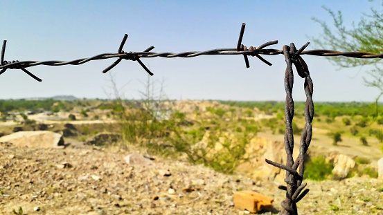 closeup of thorny iron wire for security on plateau land view from a mountain or hill
