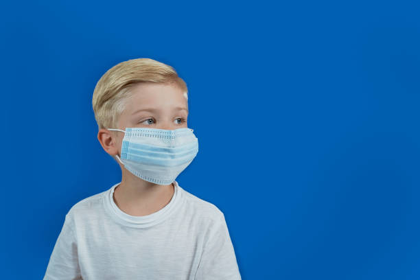 istock Boy in a medical mask looking sad 1253850427