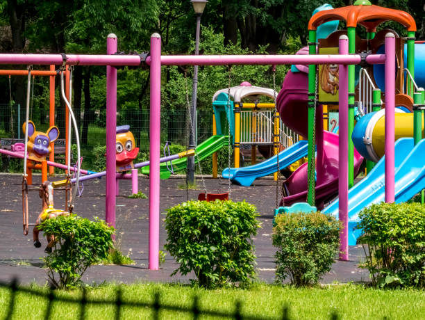 une aire de jeux pour enfants vide à bucarest, roumanie. les enfants balancent et glissent dans un parc avec des arbres. - vacant block photos et images de collection