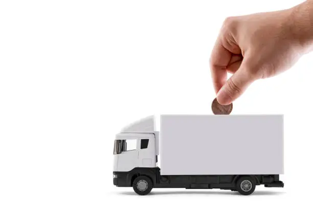 Photo of Putting coin into the white cargo delivery truck on white background
