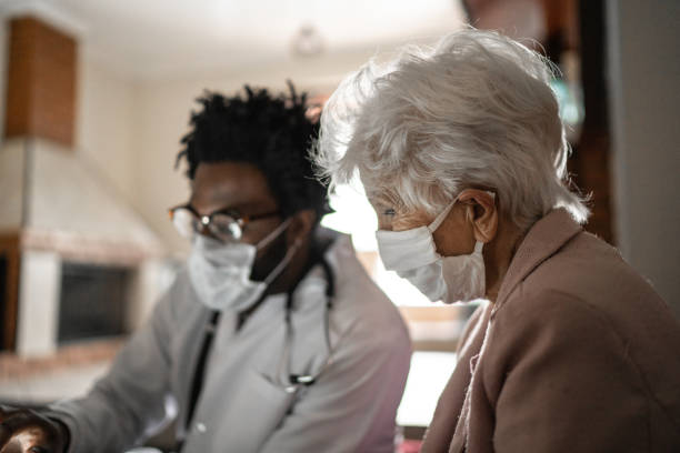 medico che usa un tablet digitale e parla con una paziente anziana a casa - consultant explaining computer home interior foto e immagini stock