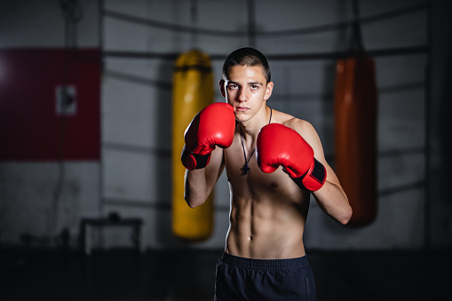 Teenage kickboxer with red boxing gloves on training.