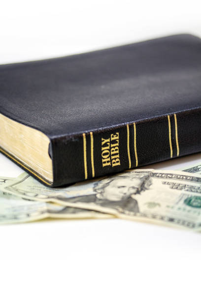 istock Holy Christian Bible with Money Isolated on White 1253857906