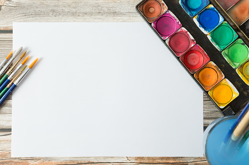 Top view of Colorful Watercolor palette, paper on a wooden table background and copy space