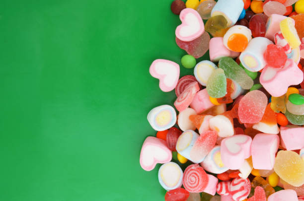 istock Colorful fruit candies and marshmallow on green background 1253863858