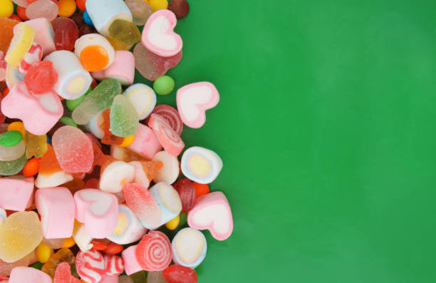 istock Colorful fruit candies and marshmallow on green background 1253863875