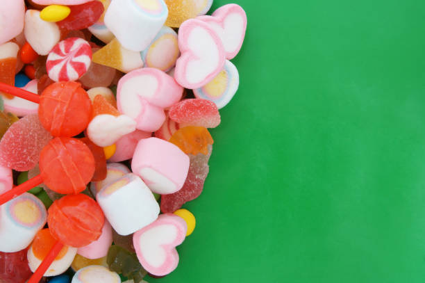 istock Colorful fruit candies and marshmallow on green background 1253863952