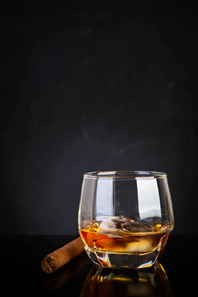 istock Glass of whiskey and cigar on dark background. 1253864149