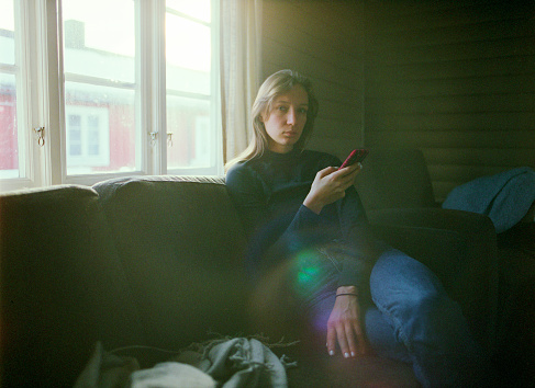 Woman sitting on sofa and using smartphone